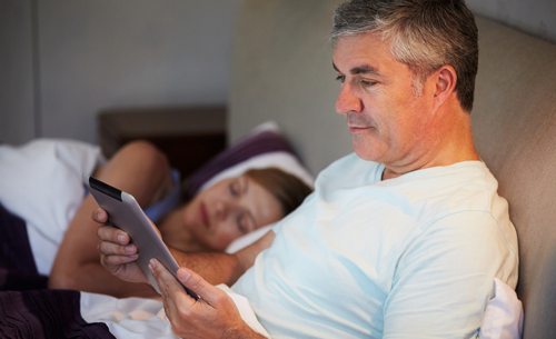 MAn in bed using tablet